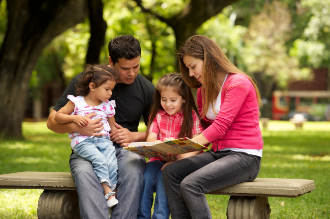 Parents reading to children at a park.