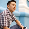 A young man ponders as he holds a copy of The Book of Mormon.