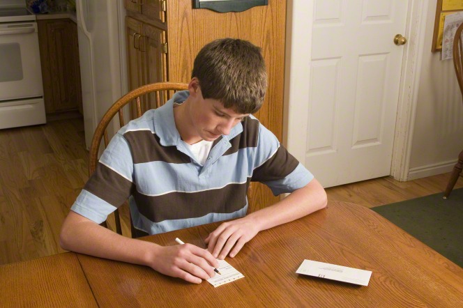 A young man fills out a tithing slip.